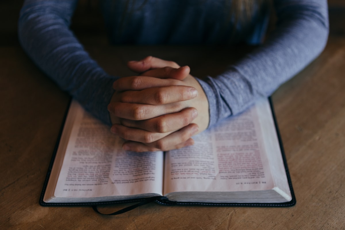 Hands resting on an open Bible in prayer